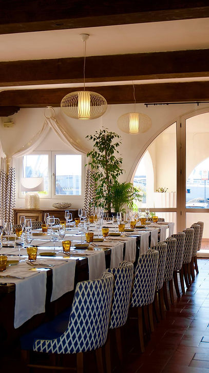 Lunga tavola da pranzo apparecchiata in una sala luminosa.