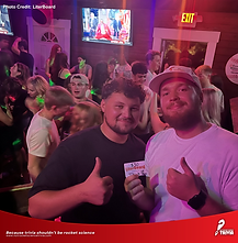 Trivia winners celebrating with a prize at LiterBoard in Knoxville during Not Rocket Science Trivia night, surrounded by a packed crowd.