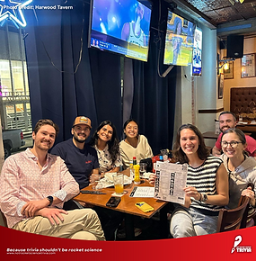 Group of trivia players smiling at their table during trivia night at Harwood Tavern in Dallas, hosted by Not Rocket Science Trivia.