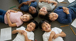 smiling-children-lying-in-a-circle-with-school-work-free-photo.jpg