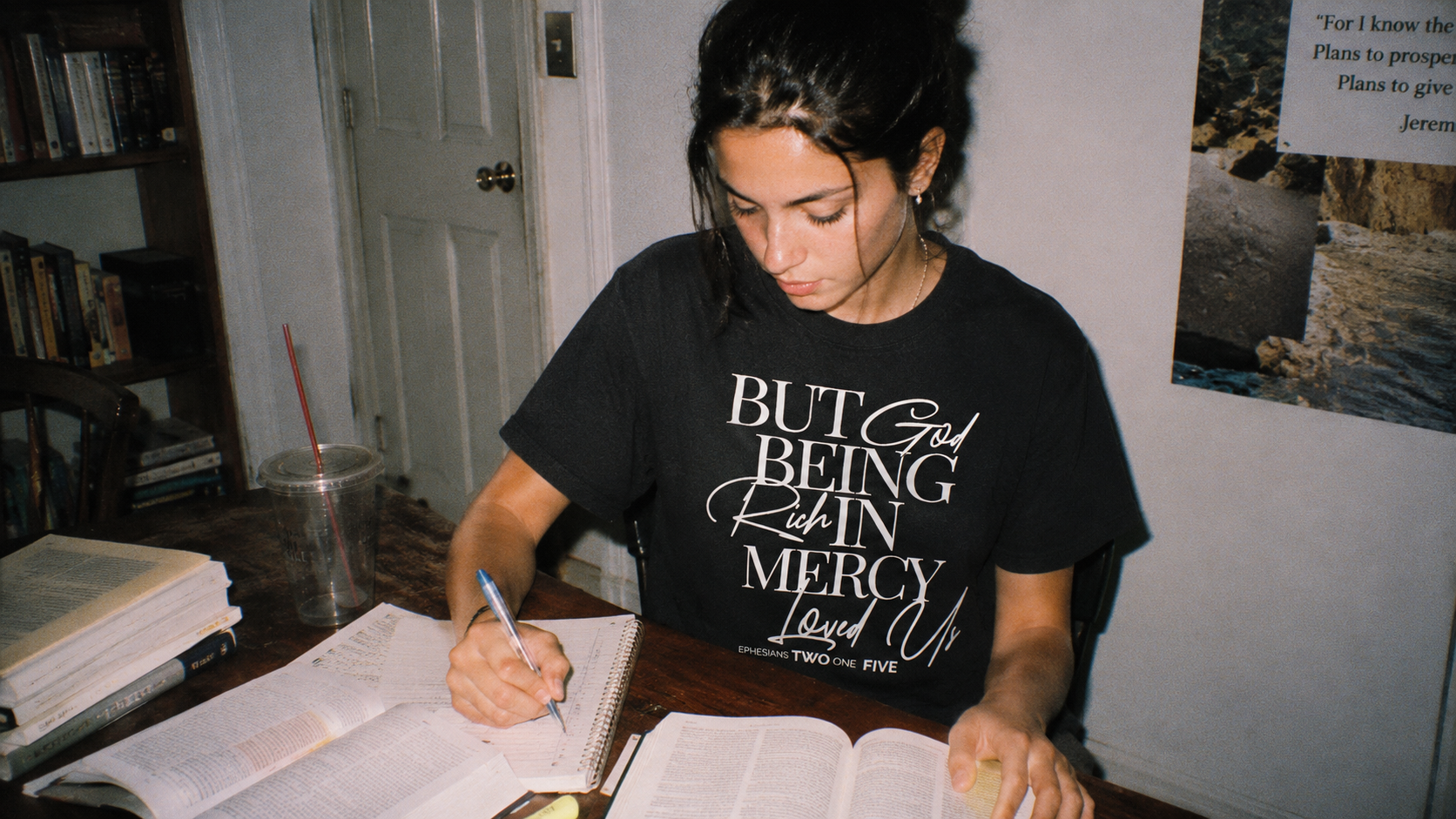 Woman in the But God Script tee studying an open Bible
