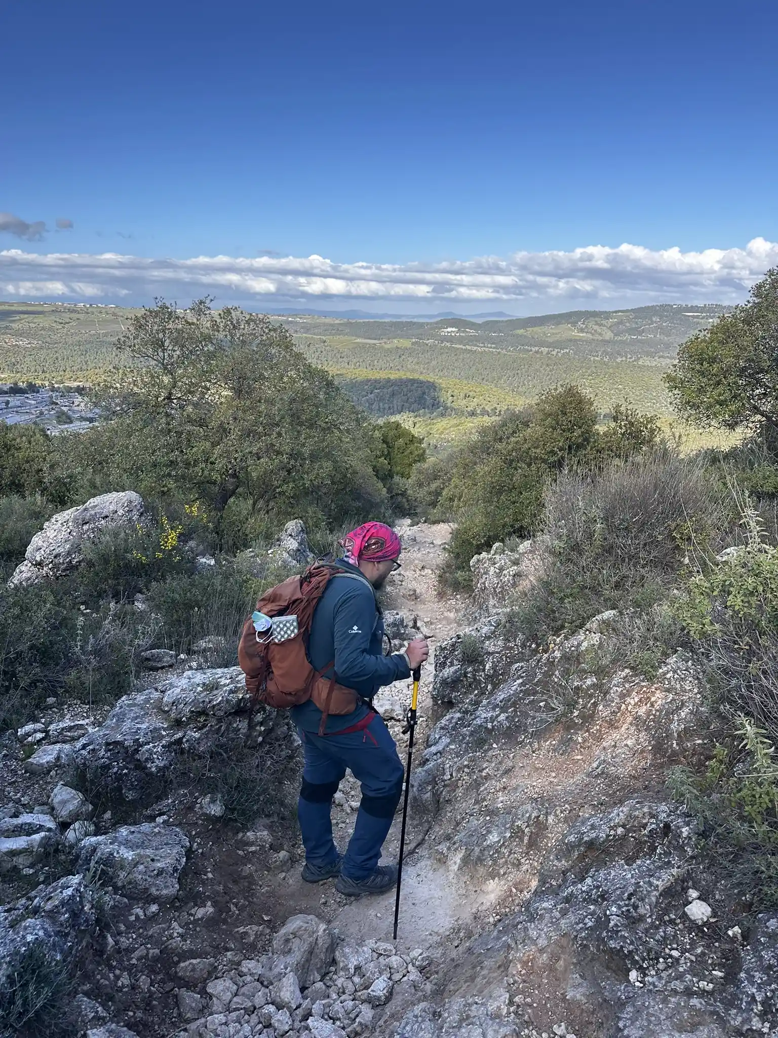мужчина с рюкзаком спускается по крутой тропе