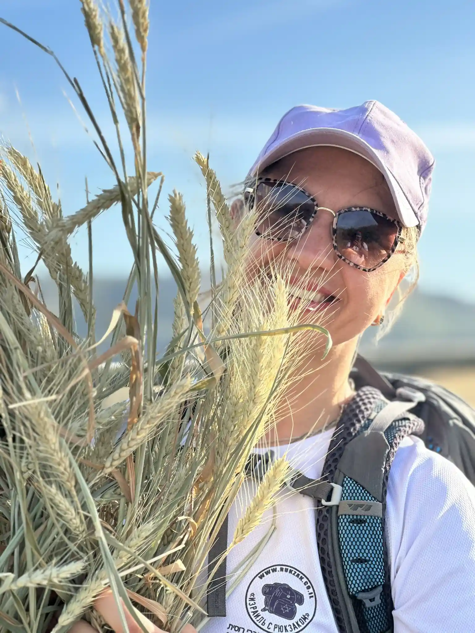 девушка в белой футболке держит колосья ржи