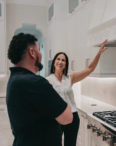 Stephanie Blake, Founder of The Limitless Designer, pointing at a range hood inside of a client's home, alongside Luis Fajardo, Construction Director for The Limitless Designer