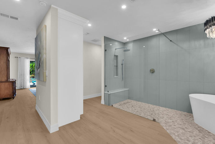 Luxury wet room renovation with freestanding tub on stone pebble floor, frameless glass enclosure, and 3D textured tile accent wall. Features a marble countertop, LED lighting, vessel sinks, and extended vanity. Modern bathroom design with new flooring, integrated LED mirrors, and innovative storage solutions. Perfect example of a spacious, spa-like master bathroom transformation with high-end finishes and a sleek, contemporary look.