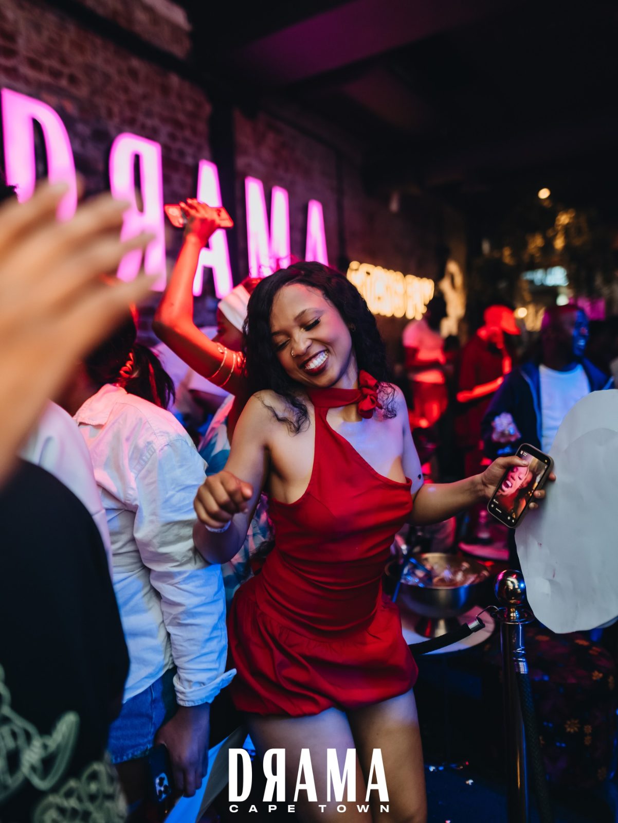 A guest dancing under the Drama neon sign