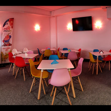 Wesoła kawiarnia z kolorowymi stolikami i krzesłami, idealna dla rodzin z dziećmi. Sala Zabaw POZYTYWKA