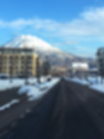 A paved road lined with the buildings of Hirafu in front of a snowcapped Mount Yotei in Niseko, Japan