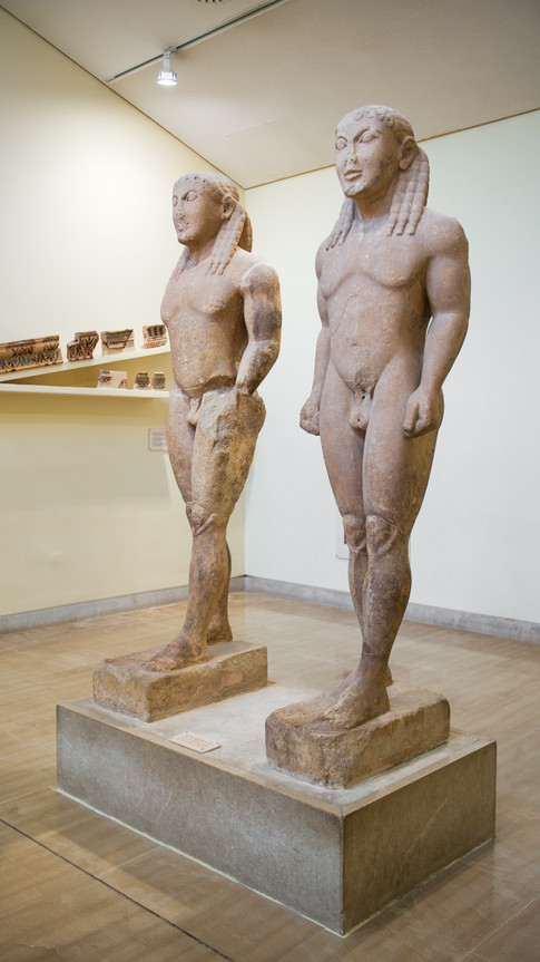 Two carved statues of naked men in the Archaeological Museum of Delphi, Greece