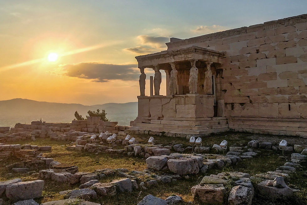 The marble brick building of the Erechetheion with its terrace of carved maiden-shaped pillars beside surrounding stone ruins on the Acropolis of Athens at sunset