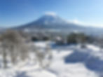 The snow-covered roads and buildings of Hirafu in front of a snowcapped Mount Yotei in Niseko, Japan