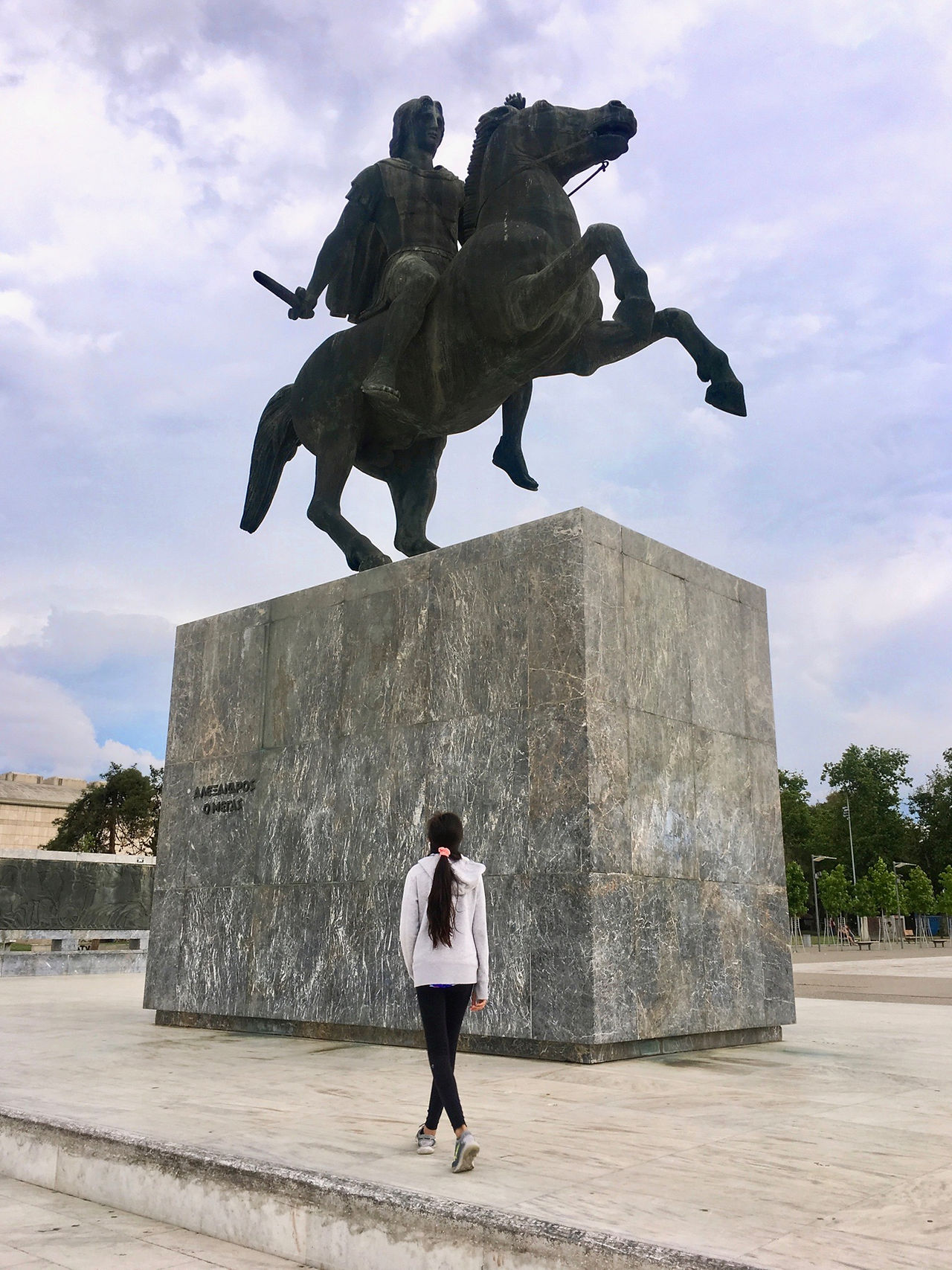 Eryn stands beneath a statue of Alexander the Great in Thessaloniki, Greece under a cloudy sky