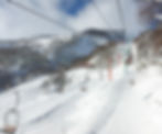 A chair lift goes up a mountainside covered in snow and leafless trees in Niseko, Japan