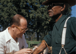The iconic photo of the Tuskegee Study depicting a white man taking blood from a black man.