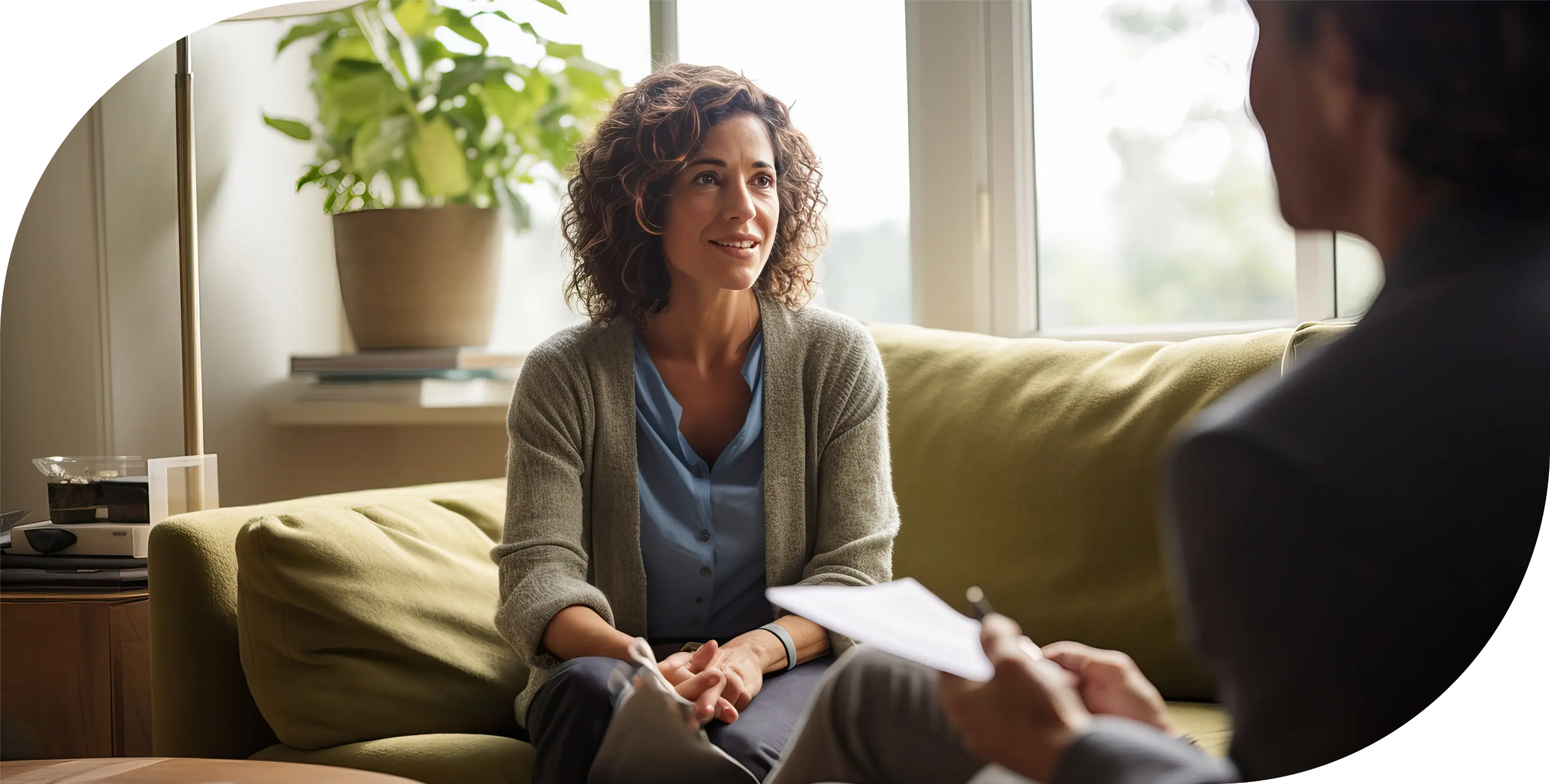 A woman sitting on a green couch talking to a counselor.
