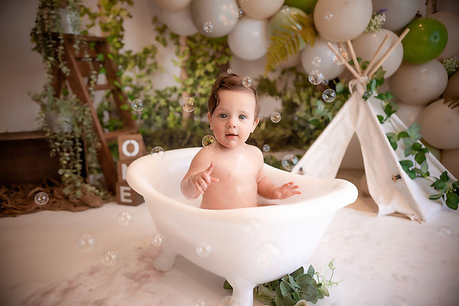 collage of baby boy celebrating his first birthday with a woodland themed cake smash