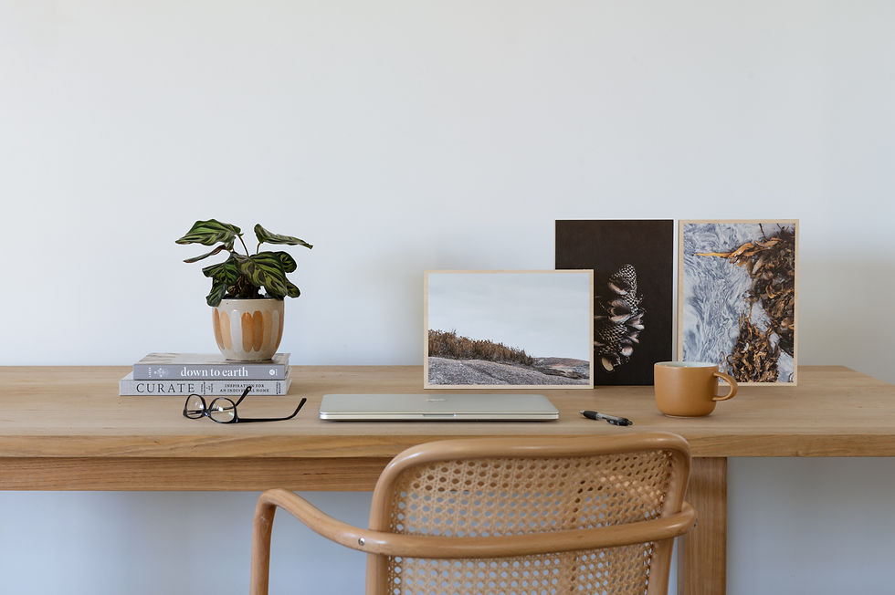 An oak desk with Australian art by Claire McFerran of Gathering Light displayed. A suggestion of a thoughtful Fathers Day gift. The desk is also styled with glasses, a mug and a laptop.