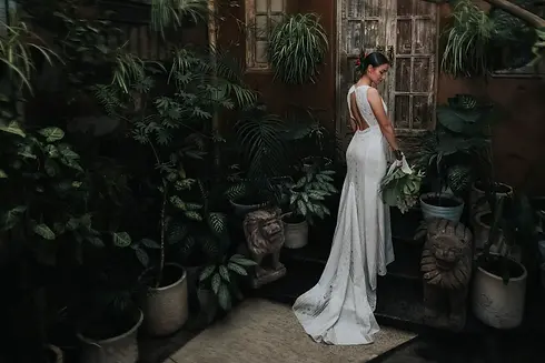 Novia de espaldas con vestido de encaje en jardín con vegetación tropical, fotografía documental de boda por Taking Moments, fotógrafo de bodas en Guadalajara.