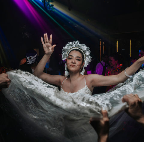 Novia celebrando bajo lluvia de confeti en recepción con luces neón.