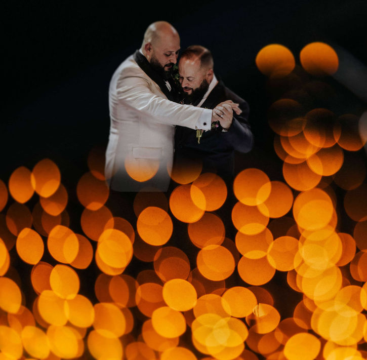 Dos novios bailando en boda igualitaria en México, fotografía documental con luces bokeh doradas
