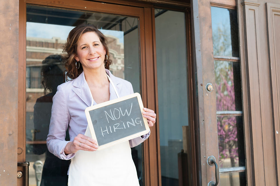 Small business owner holding "Now Hiring" sign
