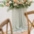 A photo of a gathered fabric table runner topped with a spray of flowers.