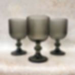 A set of three wine goblets in front of a textured backdrop.