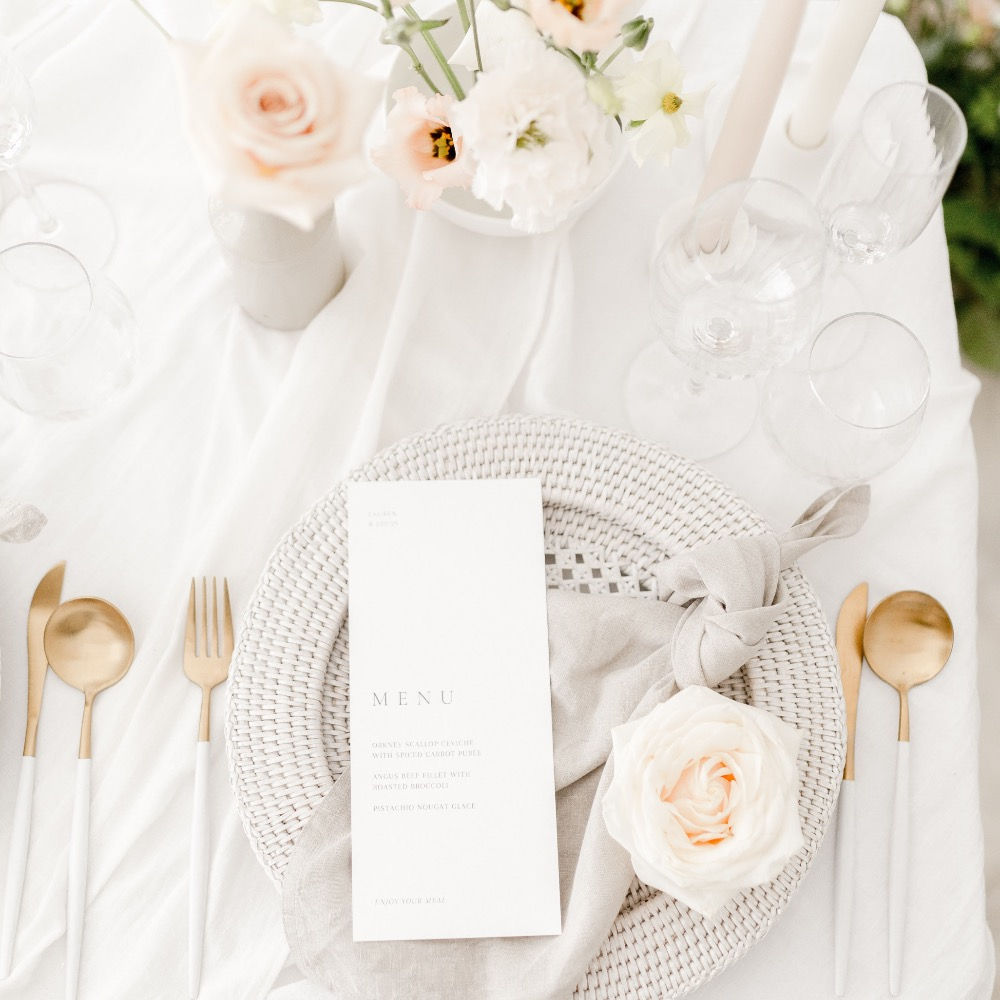 White and gold fork, knife and spoon place setting with rattan charger