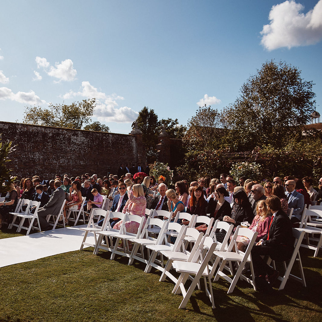 Walled garden with white folding chairs set up for a wedding ceremony