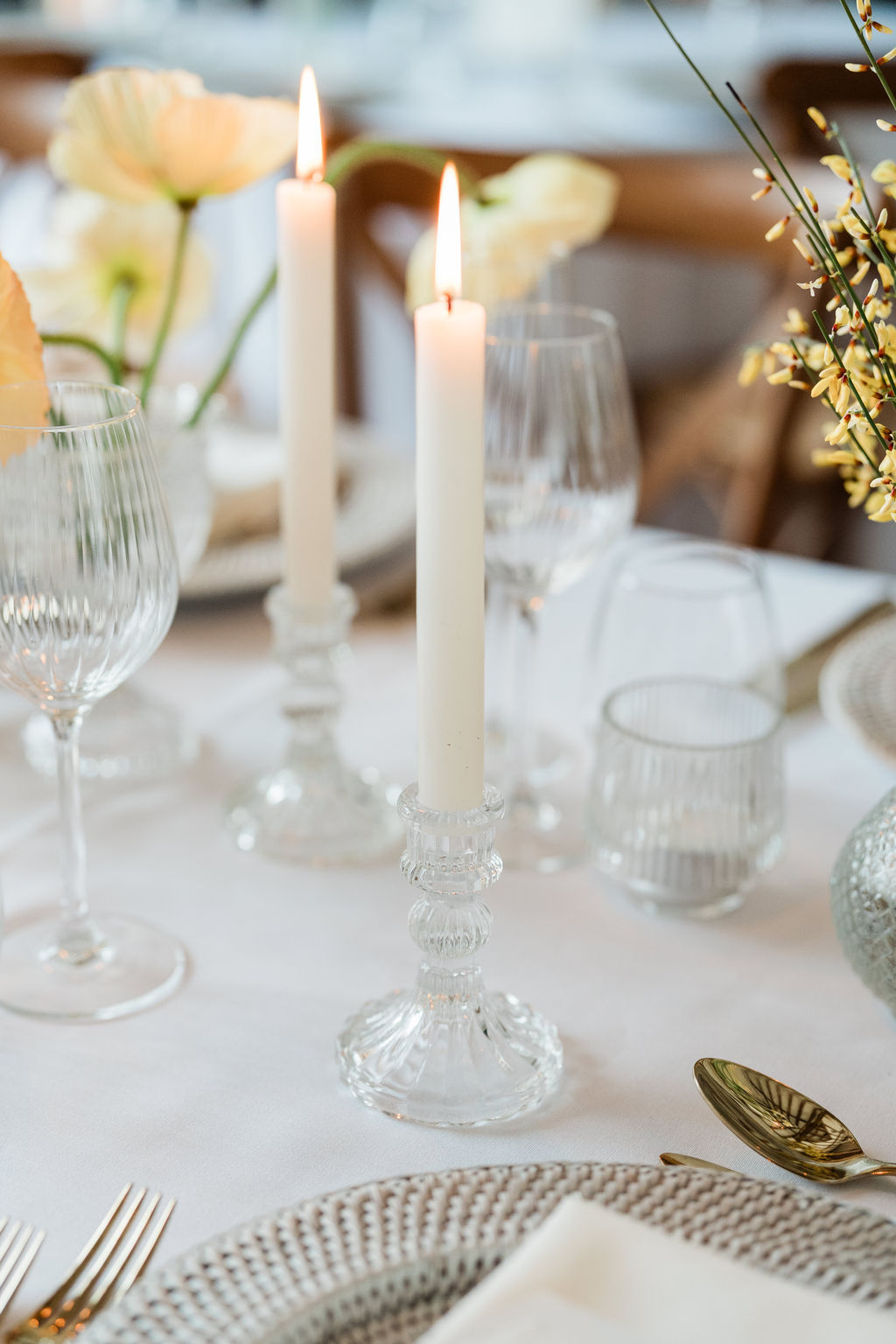 Pretty pressed glass candlesticks holding real wax ivory candles with a flickering flame