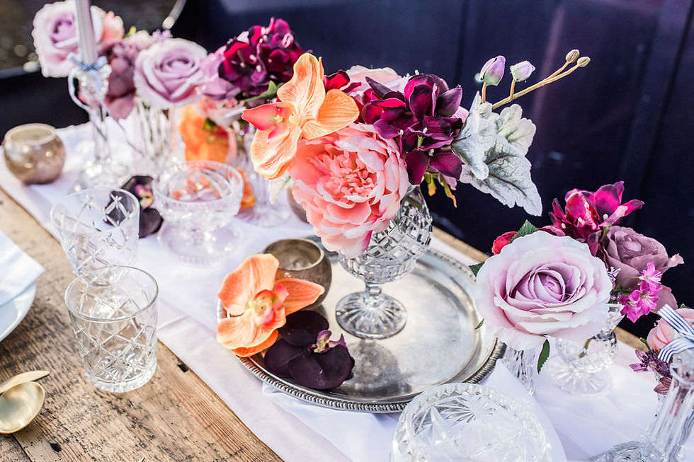 Antique silver drinks tray and floral arrangements on rustic handmade wood trestle table.