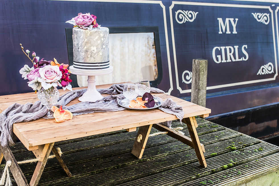 Contemporary wedding cake table styling with floral arrangements and muslin table runner, next to My Girls narrowboat on the Heybridge Basin.