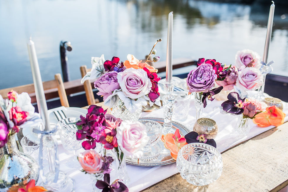 Rustic trestle sweetheart table laid with a table runner, cut glass, crystal and bud vases of bright and beautiful artificial arrangements,