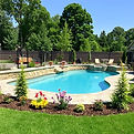 create a picture of an inground pool with a black aluminum fence and beautiful landscaping