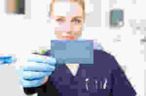 Closeup of business card hold by female dentist with copyspace