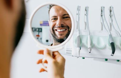 Man smiling looking in dental mirror
