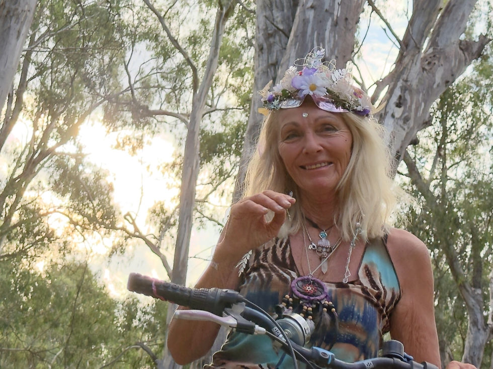 Elder woman wearing natural branch crown standing by river at sacred croning ceremony in Australia