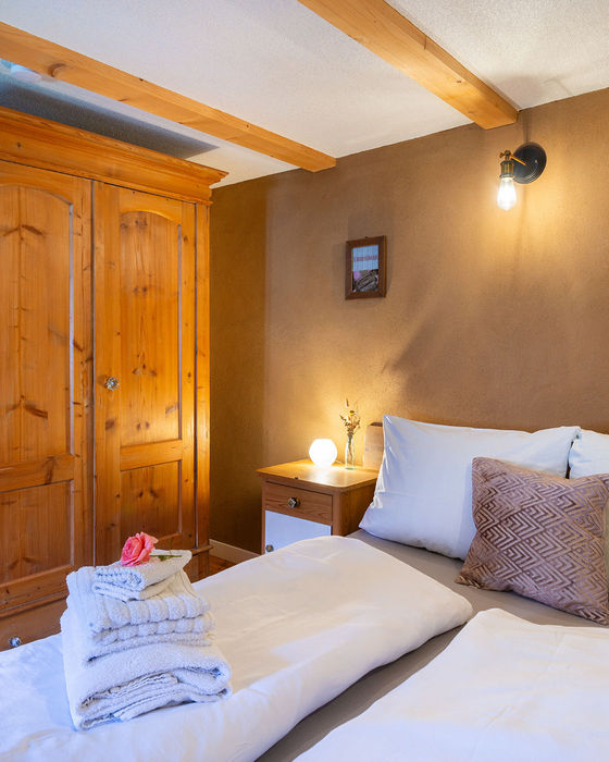 Ein Schlafzimmer mit gemachten Bett. Die Atmosphäre ist warm und einladend.