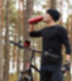 A man takes a break to drink some water and stay hydrated during a mountain bike adventure