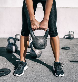 woman standing with feet apart holding a kettlebell