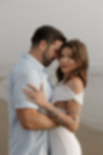 Couple embracing with ocean waves in background during Morro Bay engagement session