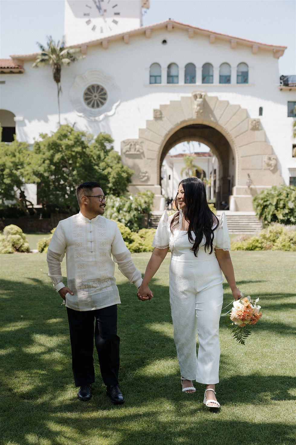Bride and groom walking through Santa Barbara Courthouse gardens by MacKenzie Rana Photography