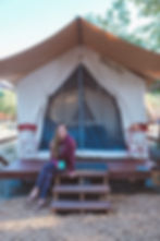 blonde woman sitting outside of a luxury glamping tent in leggings and a hoodie in California