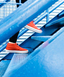 Ein Student läuft in seinen Sprachkurs und trägt Turnschuhe in orange.