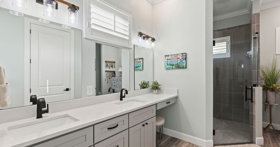 Bathroom vanity with mirror and countertop, light gray cabinets, and sink.