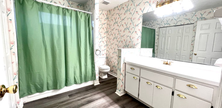 Bathroom interior with white cabinets and a green shower curtain, wallpaper.