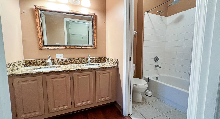 Bathroom with double sinks, mirror, and a shower/tub combination in a home.