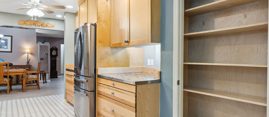 Modern kitchen with stainless steel appliances, cabinets, and empty pantry space.