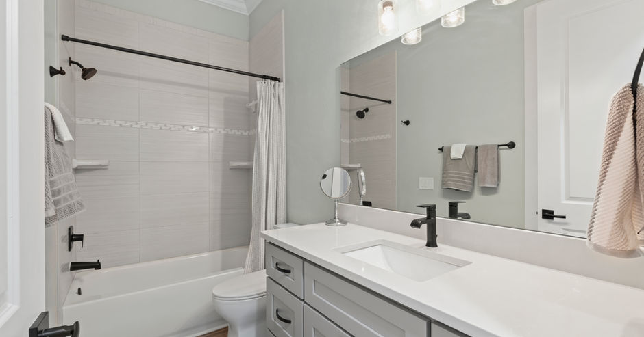 Modern bathroom with a large mirror, countertops, and a bathtub.