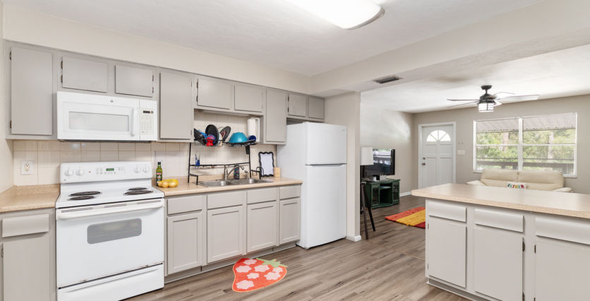 Bright kitchen with white appliances and wooden flooring; Strawberry mat visible.